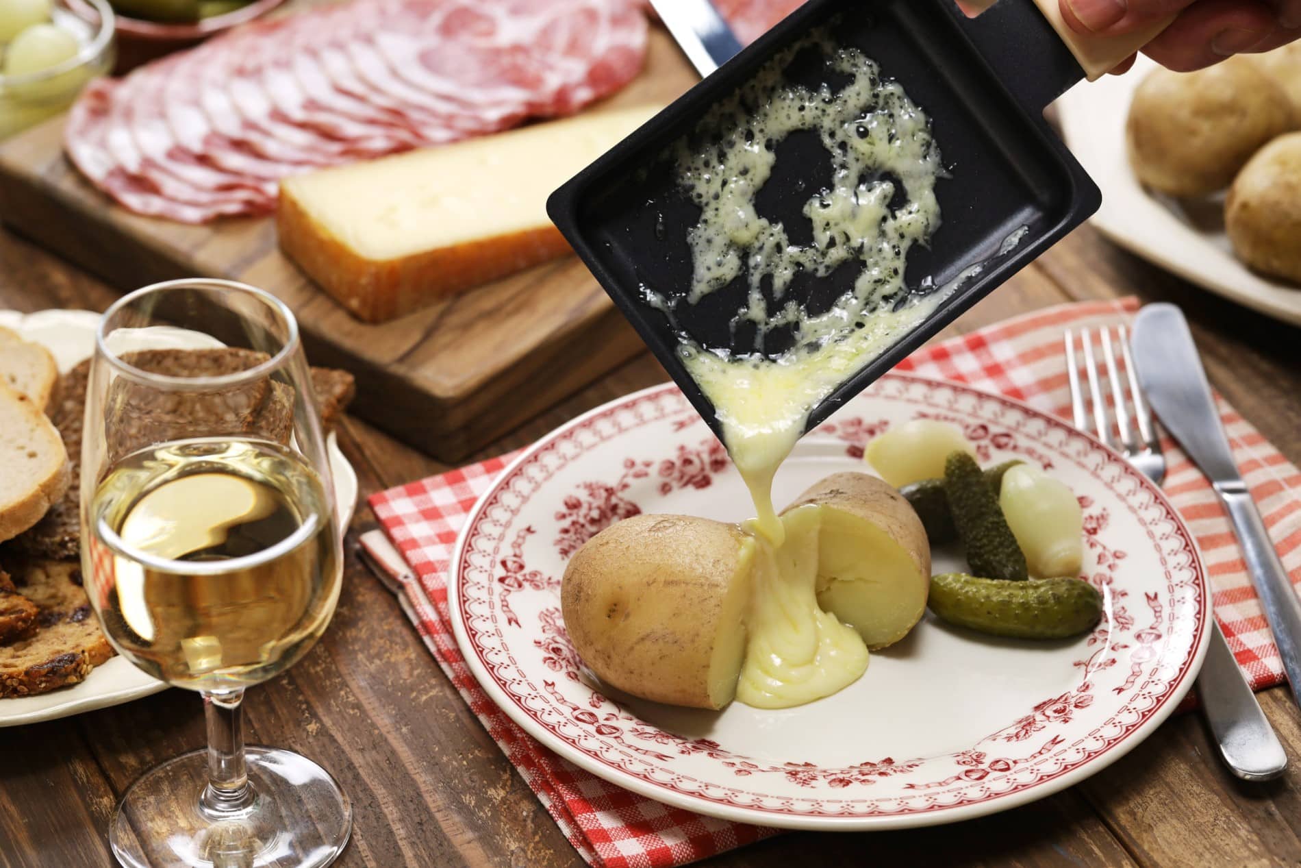 Verre de vin blanc pour accompagner une raclette fondante dans l'assiette